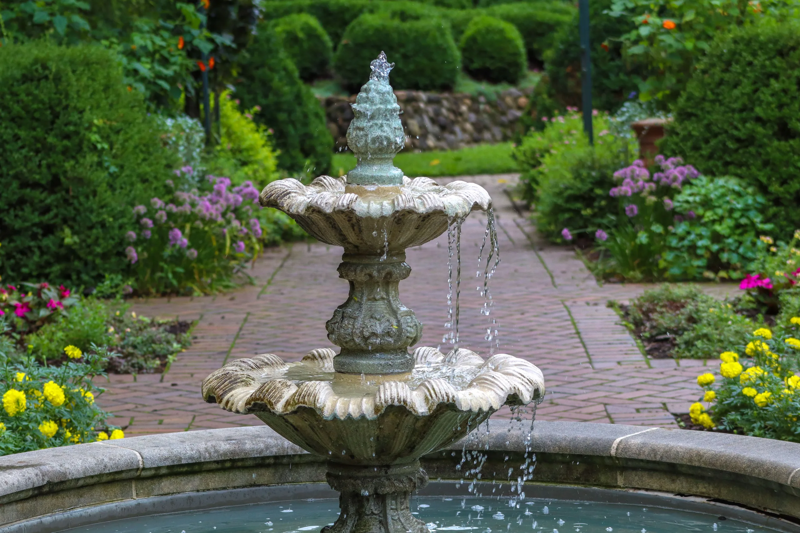 Fontaine en pierre entourée de fleurs dans un jardin verdoyant